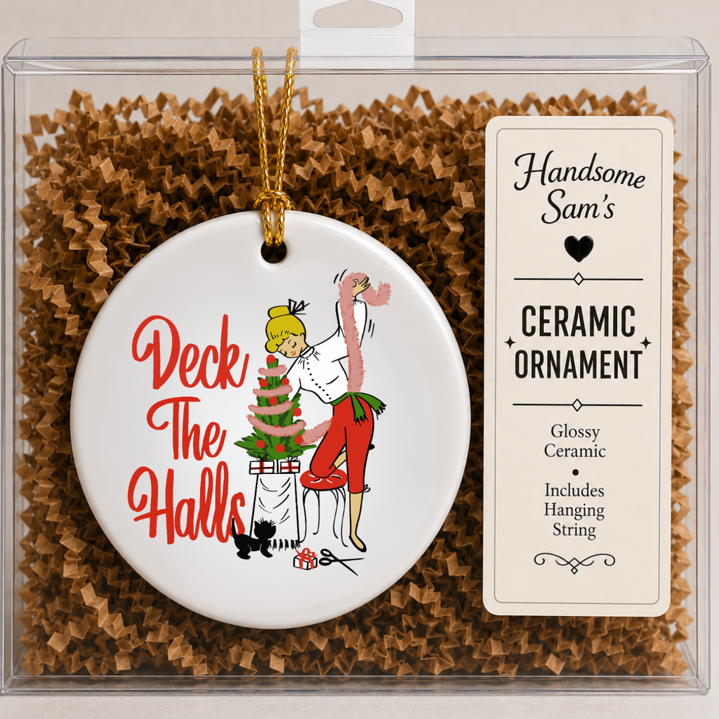 A round white ceramic Christmas ornament in clear retail packaging, featuring a retro-style illustration of a woman decorating a tree with the words 'Deck The Halls' in red. A hanging string is attached, and a label on the package reads 'Handsome Sam's' and 'Ceramic Ornament.